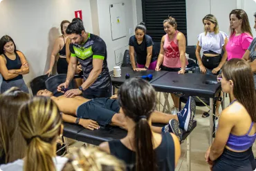 Turma reunida em volta da maca acompanhando demonstração de liberação miofascial