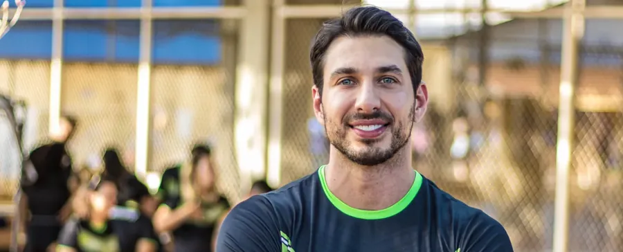 Dr. Mateus Lamari durante atendimento em evento esportivo, com a turma ao fundo
