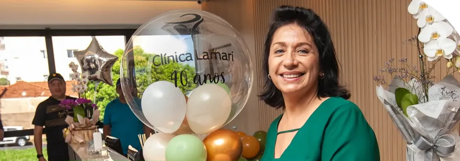 Dra. Neuseli Lamari na recepção da clínica, ao lado do balão de dez anos da Clínica Lamari